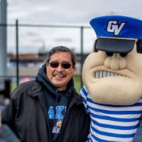 An alum takes a photo of two Lakers with Louie